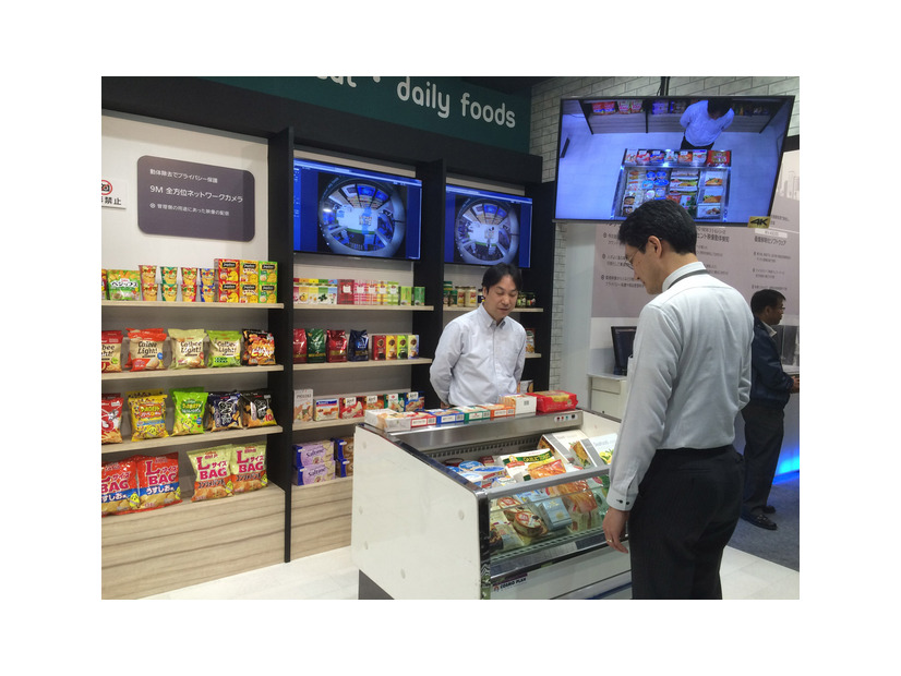 仮想店舗エリアでは冷蔵ケース（中央）や食品棚（背面）にさまざまな食品が置かれ、仮想店員が出し入れをデモ。撮影画像では、人の顔や商品判別などを確認できた。