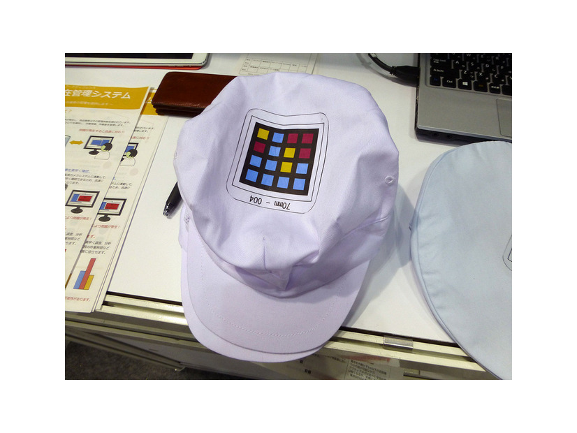 作業者の帽子などに印刷されたカラーバーコード「カメレオンコード」により入退室を監視。カメレオンコードはCMYKの4色で構成され、ブロック数の増減でデータ量は可変。作業者の個別管理には十分な情報量を持つ。