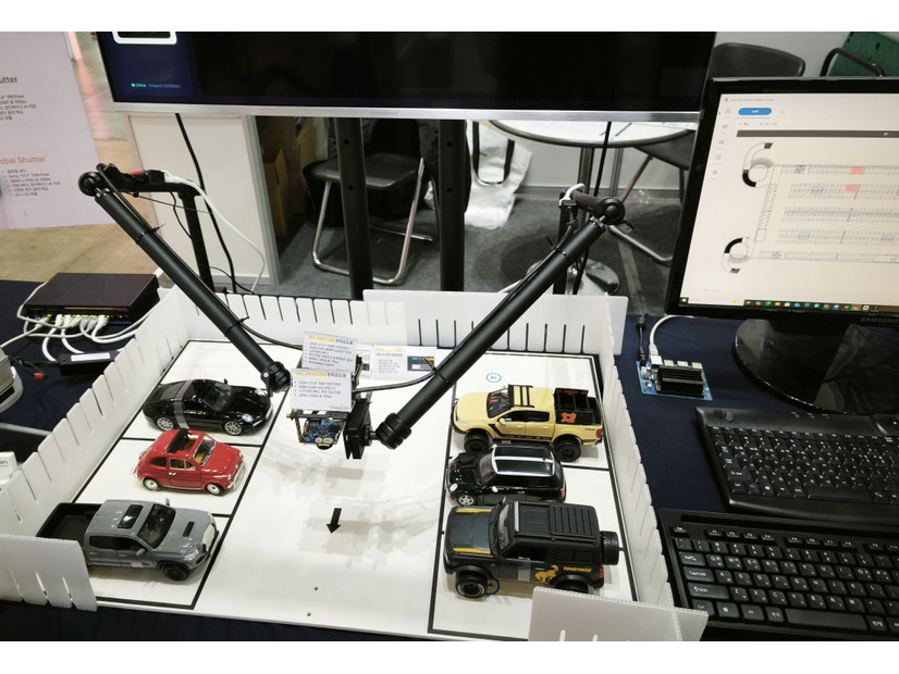駐車場の統合監視カメラシステムの模型。火災や事故の他、空きスペースの確認、予約、課金、車両の入退室管理も可能。